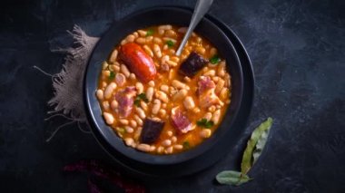 Geleneksel fasulye tarifi sucuklu ve kanlı sosis Fabada Asturiana adında karanlık bir masa üzerinde bazı malzemelerle birlikte. Tipik İspanyol yemekleri.. 
