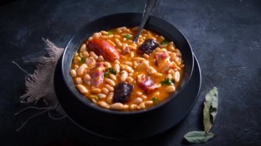 Geleneksel fasulye tarifi sucuklu ve kanlı sosis Fabada Asturiana adında karanlık bir masa üzerinde bazı malzemelerle birlikte. Tipik İspanyol yemekleri.. 