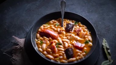 Geleneksel fasulye tarifi sucuklu ve kanlı sosis Fabada Asturiana adında karanlık bir masa üzerinde bazı malzemelerle birlikte. Tipik İspanyol yemekleri.. 