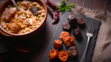 Geleneksel fasulye tarifi sucuklu ve kanlı sosis Fabada Asturiana adında karanlık bir masa üzerinde bazı malzemelerle birlikte. Tipik İspanyol yemekleri.. 