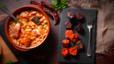 Geleneksel fasulye tarifi sucuklu ve kanlı sosis Fabada Asturiana adında karanlık bir masa üzerinde bazı malzemelerle birlikte. Tipik İspanyol yemekleri.. 