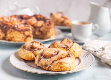 Kahvaltıda kahve ve hamur işi çöreklerle beyaz bir masada beyaz bir tabakta ev yapımı tarçınlı rulo. Geleneksel İsveççe ve Danimarka tarifi.