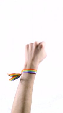 El, barış ya da zaferin sembolü olarak iki parmağını gösteren LGBT bayrağı renginde bir bilezik takıyor. LGBT sembolü. Dikey video.