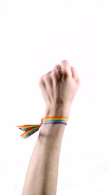 Hand wearing a bracelet with the colors of the LGBT flag raising thumb. LGBT symbol. Vertical video.