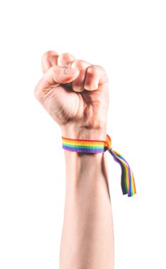 Kolumda LGBT bayrağı renginde bir bilezik var. Güç ve mücadelenin sembolü olarak yumruğu kapatıyor. LGBT sembolü.