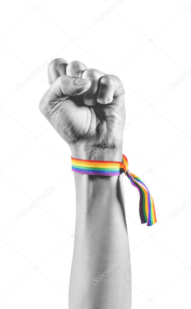 Black and white arm wearing a bracelet with the colors of the LGBT flag closing the fist as a symbol of strength and struggle. LGBT symbol.
