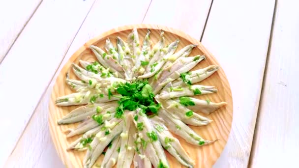 用大蒜和欧芹在白色木制桌子上的圆形木制盘子里挑食的凤尾鱼 典型的西班牙小吃 — 图库视频影像