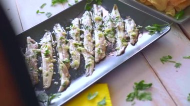 Üç tabak patates cipsi, ançüez ve yeşil zeytinleri maydanoz yapraklı beyaz ahşap bir masada topladım. Barda yemek için tipik İspanyol atıştırmalıkları..