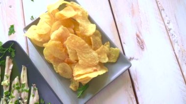 Üç tabak patates cipsi, ançüez ve yeşil zeytinleri maydanoz yapraklı beyaz ahşap bir masada topladım. Barda yemek için tipik İspanyol atıştırmalıkları..