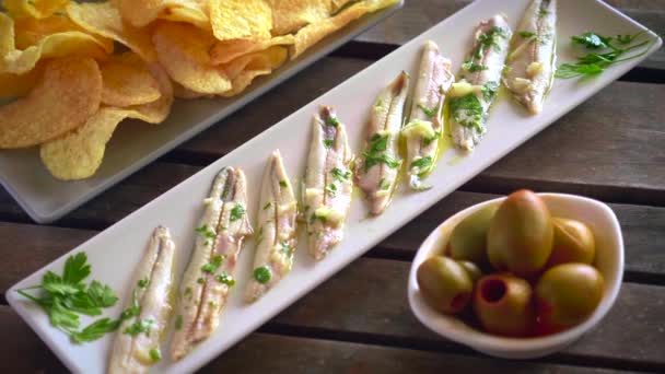 三道菜 马铃薯片 采摘的凤尾鱼和绿色橄榄在黑暗的木制桌子上与牙签 在酒吧里吃的典型西班牙小吃 — 图库视频影像