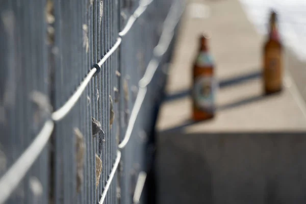 灰色の花崗岩の石で満たされた鉄棒で作られたガビオンフェンス ビールボトル付きの公園のベンチ サイドビュー ドイツの冬 — ストック写真