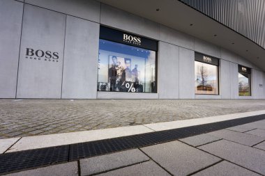 Metzingen, Almanya - 20 Mart 2021 Hugo Boss Outlet mağazası. Dükkan vitrinleri siyah cephe altında. Ön planda kaldırım taşları var. Yan görünüm.