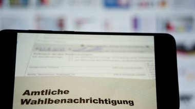 Stuttgart, Almanya - 29 Ağustos 2021. Almanya 'daki 2021 federal seçimleri için resmi seçim bildirisi. Belgeli akıllı telefon. Arka planda seçim temalı bilgisayar monitörü. Yakın çekim..