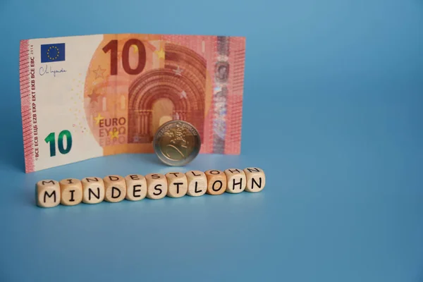 Tahta zarlar üzerindeki harfler: asgari ücret (Almanca: mindestlohn). Almanya 'daki işçilere adil ücret ödenmesi için siyasi partilerin temasına katkıda bulunun. 12 Euro asgari ücret.