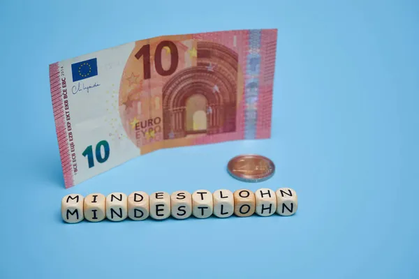 Tahta zarlar üzerindeki harfler: asgari ücret (Almanca: mindestlohn). Almanya 'daki işçilere adil ücret ödenmesi için siyasi partilerin temasına katkıda bulunun. 12 Euro asgari ücret. Boşluğu kopyala.