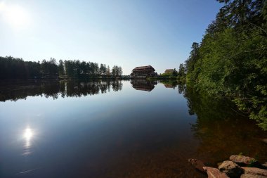 Hornisgrinde, Almanya - 11 Ağustos 2021: Kuzey Kara Orman 'da (Mummelsee). Ağaçların yansıdığı sakin bir su. Bir geceliğine otel diğer kıyıda kalıyor..