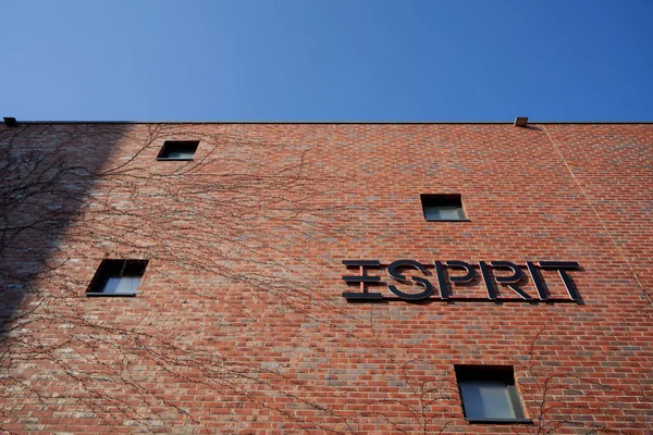 Metzingen, Almanya - Mai 03, 2021: Esprit moda logosu. Kırmızı tuğlalı duvarda siyah harfler. Dört pencere. Kopyalama alanı için mavi gökyüzü.