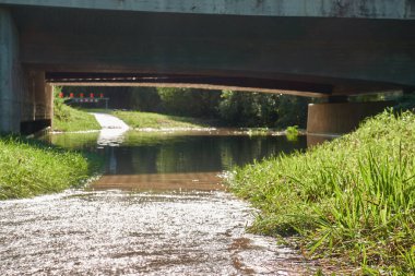 Şiddetli yağmurdan sonra yolu su bastı. Nehir taşar ve köprünün altından geri çekilir..