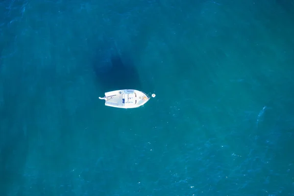 Atlantik 'in yukarısından gelen boş bir balıkçı teknesi. Mavi deniz suyundaki küçük beyaz geminin havadan görünüşü. Ayrı nesne.