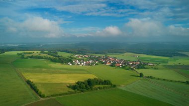 Küçük bir köy. Swabian Alb 'inde sağanak yağmurdan sonra manzara. Beyaz bulutlu mavi gökyüzü. Tarım alanları. Drone bakış açısı.