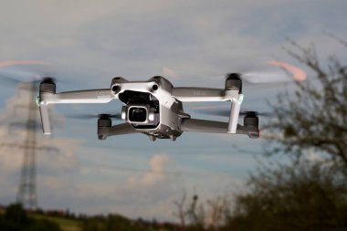 Nurtingen, Almanya - 26 Haziran 2021: Dji şirketinin İHA 2 'leri havada süzülüyor. Mavi bulutlu gökyüzünün önünde elektrik direği ve çıplak ağaç. Düşük açı görünümü.