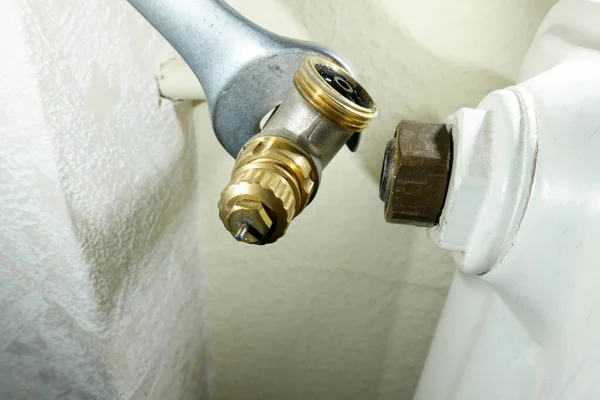 Eski radyatör termostat vanasını değiştir. Alet ısıtıcıdan bileşeni kaldırır. Isıtma sistemlerinin modernizasyonu. Yüksek açı görünümü.