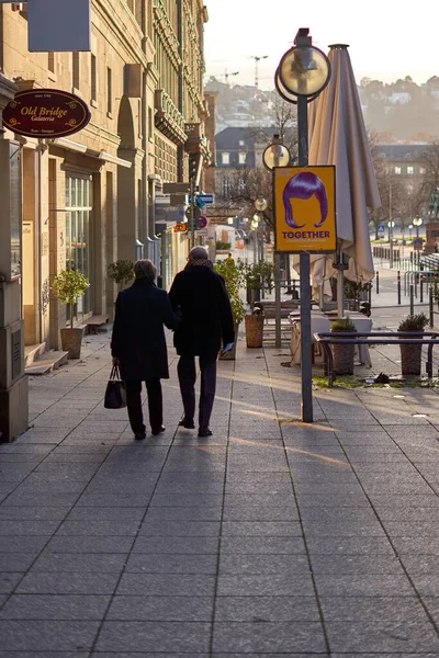 Stuttgart, Almanya - 06 Ocak 2022: Yaşlı bir çift şehirde birlikte yürüyor. Siyah elbiseli yaşlılar vitrinlere bakıyor. Dikiz aynası. Stuttgart, Almanya.