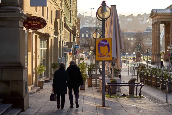 Stuttgart, Almanya - 06 Ocak 2022: Yaşlı bir çift şehirde birlikte yürüyor. Siyah elbiseli yaşlılar vitrinlere bakıyor. Dikiz aynası. Stuttgart, Almanya.