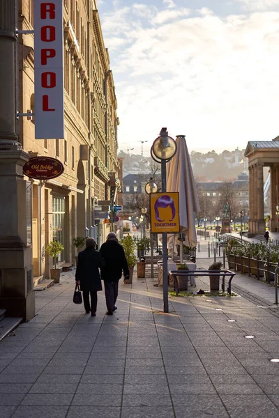 Stuttgart, Almanya - 06 Ocak 2022: Yaşlı bir çift şehirde birlikte yürüyor. Siyah elbiseli yaşlılar vitrinlere bakıyor. Dikiz aynası. Stuttgart, Almanya.