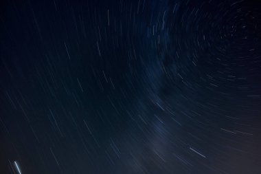 Karanlık gece gökyüzünde yıldız izleri. Kuzey yıldızı sağ üstte. Uzun pozlama, hareket bulanık.