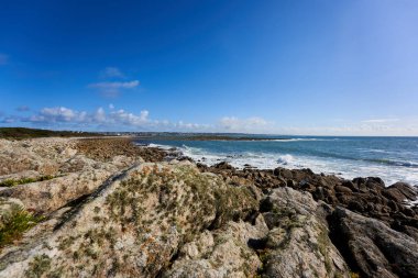 Breton sahilindeki kayalar. Mavi gökyüzüne karşı deniz suyuyla kaplı bir manzara. Kayalık arka plan. Fransa, İngiltere, Audierne, Lervily.