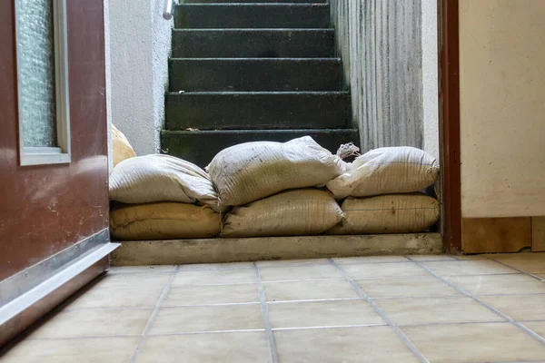 Protective measure against floods in basements. Barrier made of sandbags lies in the entrance area of a residential building.