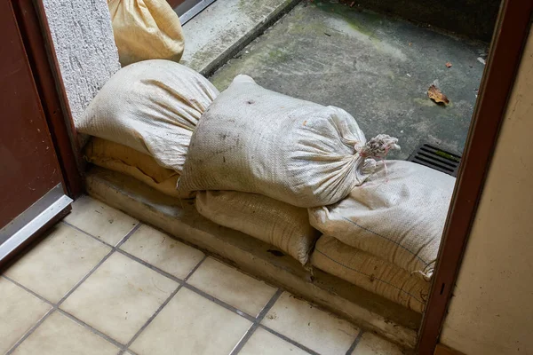 Protective measure against floods in basements. Barrier made of sandbags lies in the entrance area of a residential building. Closeup.