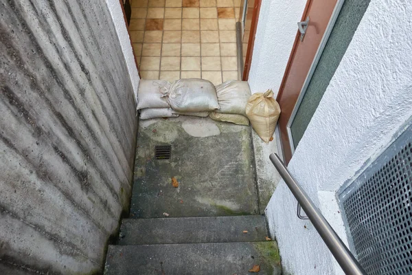 Protective measure against floods in basements. Barrier made of sandbags lies in the entrance area of a residential building. Top view.