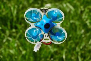 Küçük mavi İHA da yarışta, beyazlı koruyucu gondol ve bulanık yeşil arka plan. Almanya.