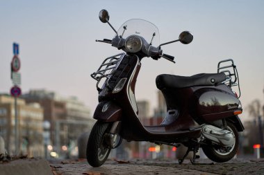Stuttgart, Almanya - 31 Aralık 2021: Vespa scooter 'ı. Sokak lambaları yanmadan önce iki tekerlek üzerinde hareket.