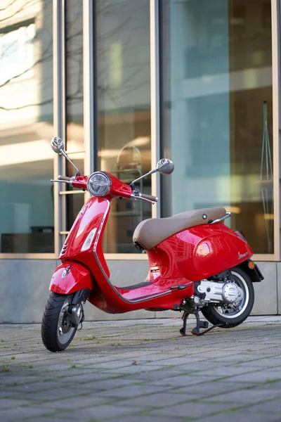Stuttgart, Almanya - 31 Aralık 2021: Red vespa scooter in the city. Modern şehir mimarisinin önünde iki tekerlek üzerinde hareket kabiliyeti.