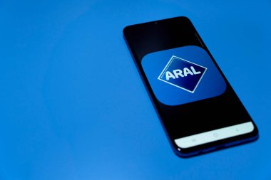 Stuttgart, Almanya - 10 Nisan 2022: Yakıt fiyatı uygulamalı akıllı telefon (Aral Aktiengesellschaft). Pahalı benzinle ucuz yakıt ve enerji masrafları. Mavi üzerine izole edilmiş..