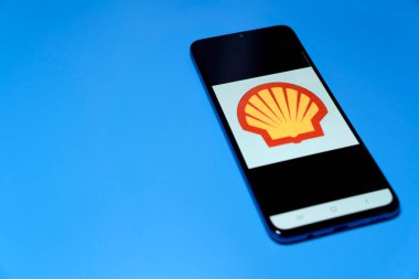 Stuttgart, Germany - April 10, 2022: Smartphone with fuel price app (Shell B.V.). Cheap refueling with expensive gas, and energy costs. Isolated on blue.