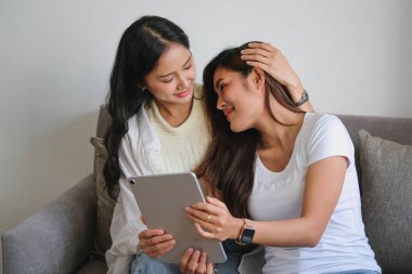 Igbtq, Igbt konsepti, homoseksüellik, birbirine aşık iki güzel kadın, sıcak bir evde mutlu bir şekilde tablet oynuyorlar.