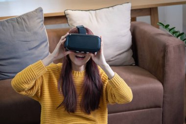 Tatilde stresten kurtuldum. Mutlu Asyalı kadın evde dinleniyor. Tatilde VR 3 boyutlu sanal gerçeklik oyunu oynuyor..