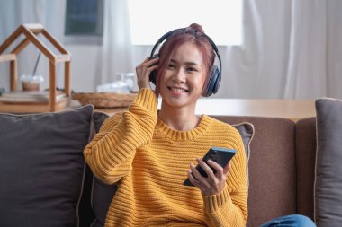 Rahatla, stres at, tatil yap, mutlu, Asyalı kadın evde rahatla akıllı telefondan ve bilgisayardan mutlu bir şekilde müzik dinle..