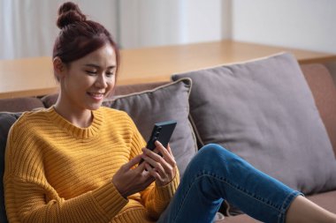 Rahatla, stres at, tatil yap, mutlu, Asyalı kadın evde rahatla akıllı telefondan ve bilgisayardan mutlu bir şekilde müzik dinle..