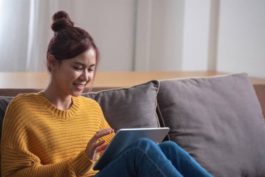 Rahatla, stres at, tatil yap, mutlu, Asyalı kadın evde rahatla akıllı telefondan ve bilgisayardan mutlu bir şekilde müzik dinle..