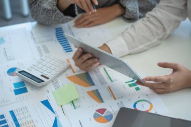 İş kadınları, pazarlama stratejileri planlamak ve şirket için kârlı yatırımlar yapmak için hesap makineleri ve grafik analizi bilgisayar tabletleri kullanır..