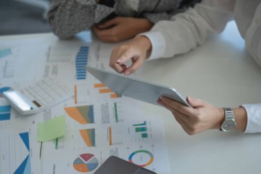 Team of business women use calculators and graph analysis computer laptop tablets to plan marketing strategies and make profitable investments for the company.