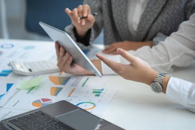 Team of business women use calculators and graph analysis computer laptop tablets to plan marketing strategies and make profitable investments for the company.