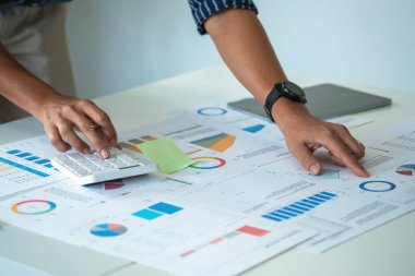 İş adamları pazarlama stratejileri planlamak ve şirkete kârlı yatırımlar yapmak için hesap makineleri ve grafik analizi laptopları kullanıyorlar..