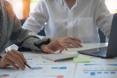Team of business women use calculators and graph analysis computer laptop tablets to plan marketing strategies and make profitable investments for the company.