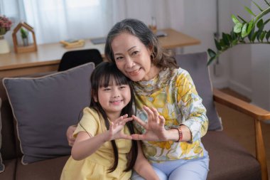 Bir büyükanne ve torunun portresi, aile içinde sıcaklık ve sevgi yaratmak için ev aktiviteleri yapıyor ve birbirlerine sevgi gösteriyorlar..